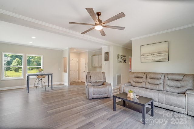 living area with light wood-style flooring, visible vents, baseboards, and ornamental molding