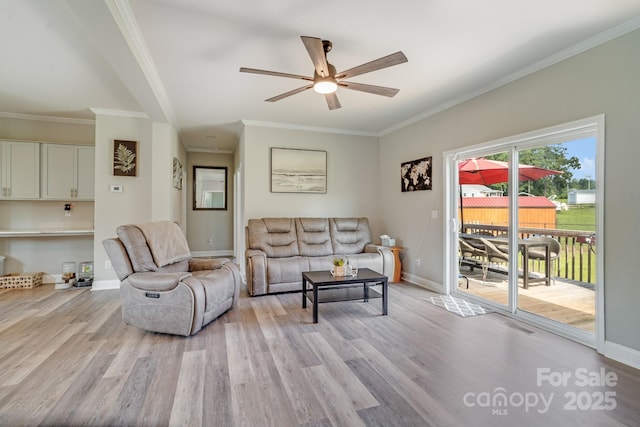 living room featuring light wood-style floors, baseboards, a ceiling fan, and ornamental molding