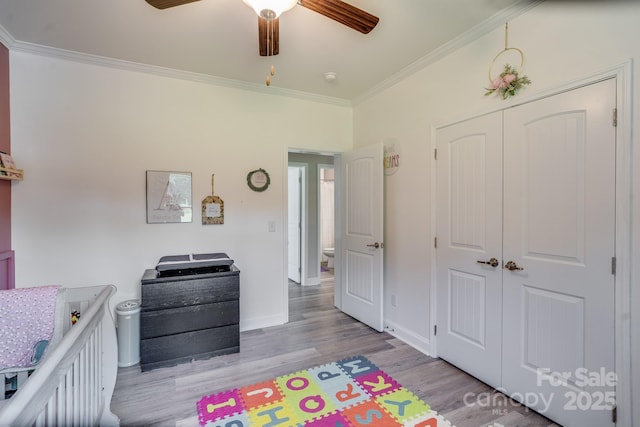 bedroom featuring baseboards, ceiling fan, crown molding, light wood-type flooring, and a closet