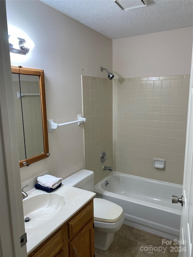 full bathroom with vanity, a textured ceiling, toilet, and tiled shower / bath