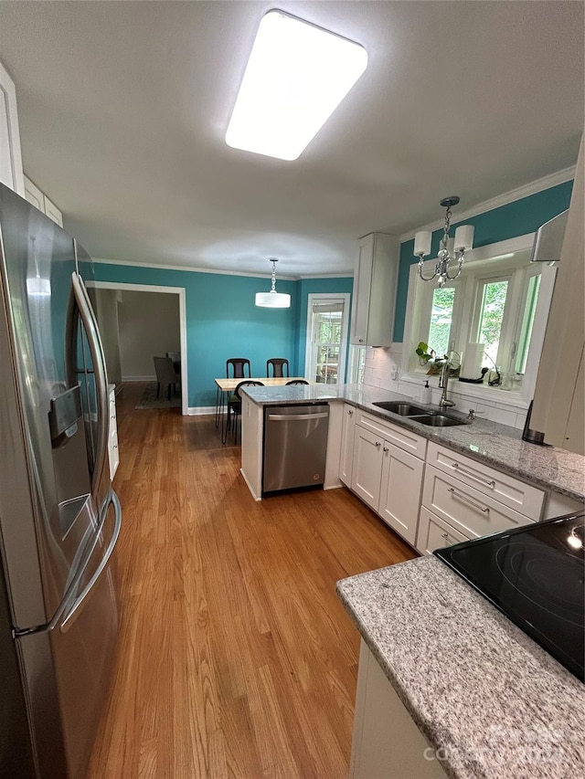 kitchen with appliances with stainless steel finishes, a wealth of natural light, sink, and light hardwood / wood-style floors