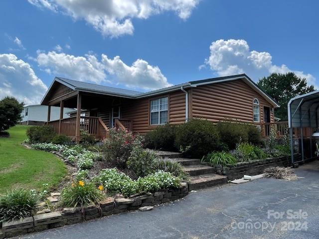 log cabin featuring a carport and covered porch