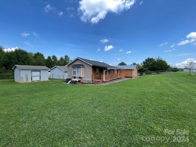 back of property with a wooden deck, a lawn, and a storage unit