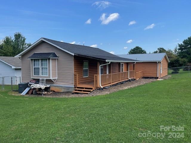 rear view of property featuring a deck and a lawn