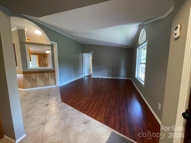 spare room with vaulted ceiling, crown molding, and hardwood / wood-style flooring