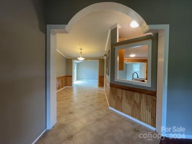 hallway featuring crown molding and wood walls