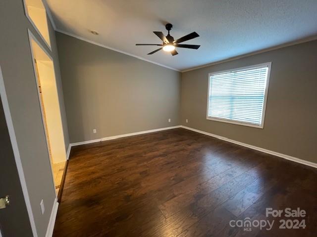 spare room with ceiling fan, ornamental molding, and dark hardwood / wood-style flooring