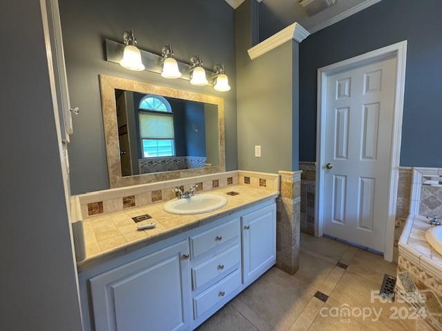 bathroom with tiled tub, tile patterned flooring, vanity, and ornamental molding