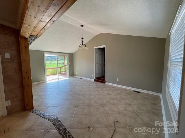 tiled spare room featuring vaulted ceiling and a textured ceiling