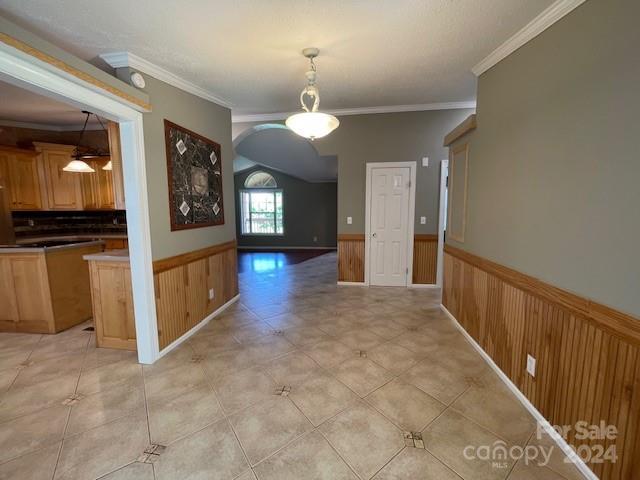 unfurnished dining area featuring light tile patterned floors, ornamental molding, and wood walls