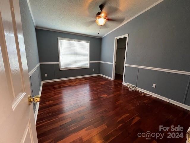 empty room featuring ornamental molding, hardwood / wood-style flooring, a textured ceiling, ceiling fan, and lofted ceiling