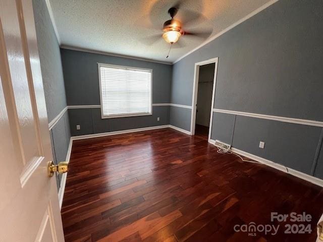 spare room with ornamental molding, dark wood-type flooring, ceiling fan, and a textured ceiling