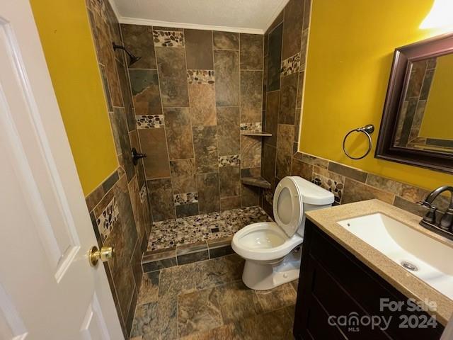 bathroom featuring tile walls, toilet, a tile shower, and vanity