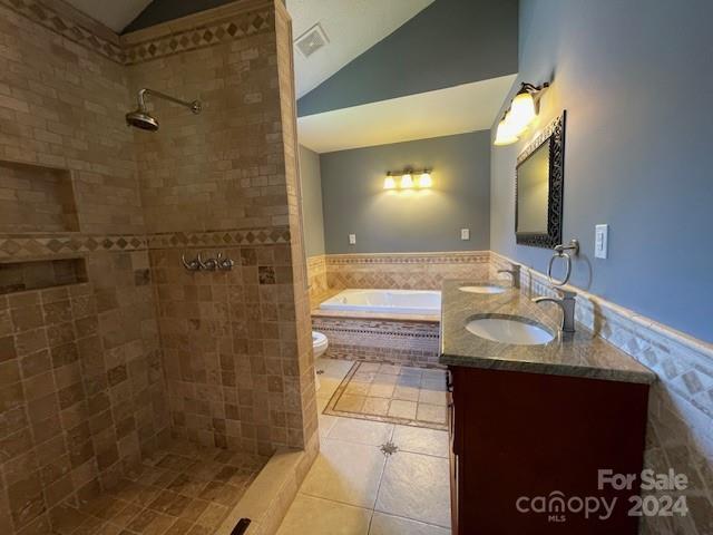 full bathroom featuring vaulted ceiling, tile patterned flooring, independent shower and bath, dual bowl vanity, and toilet