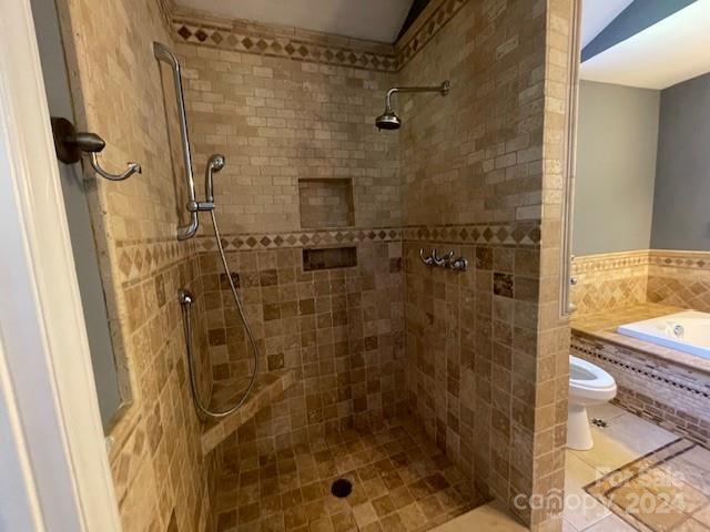 bathroom with tile patterned floors, toilet, and a tile shower