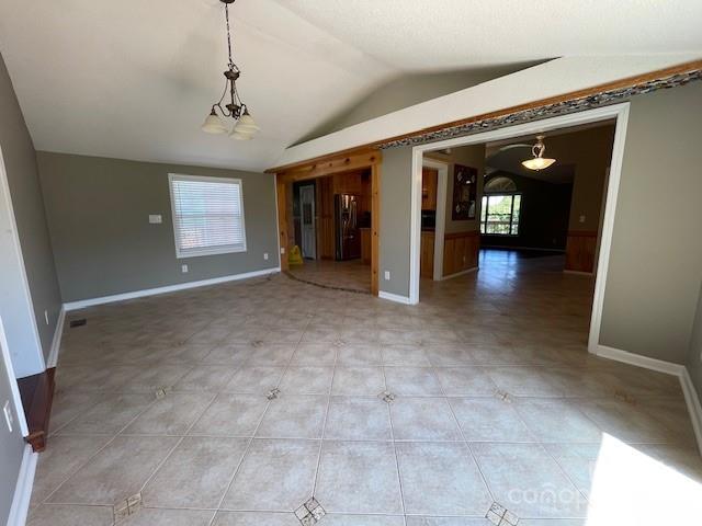 empty room with tile patterned floors, lofted ceiling, and a chandelier