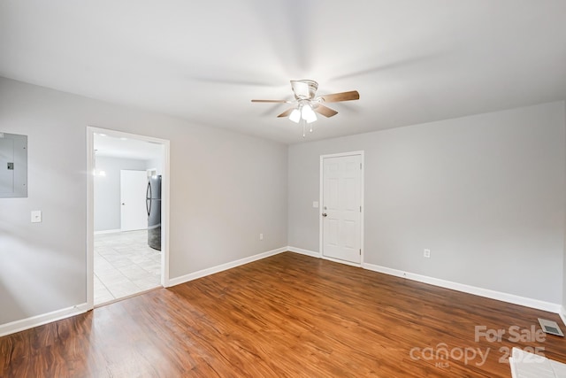 unfurnished room with electric panel, ceiling fan, and light hardwood / wood-style floors