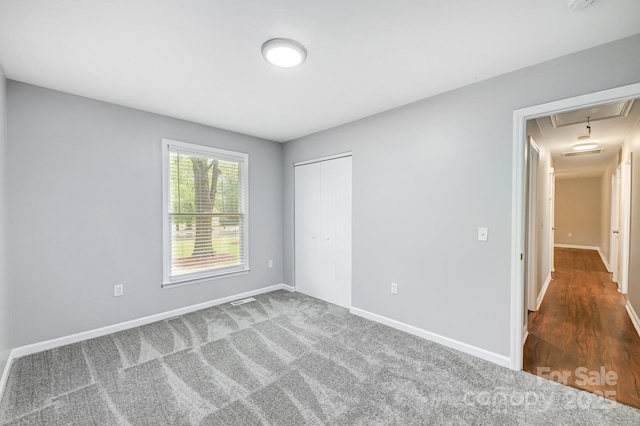 unfurnished bedroom with a closet and dark colored carpet