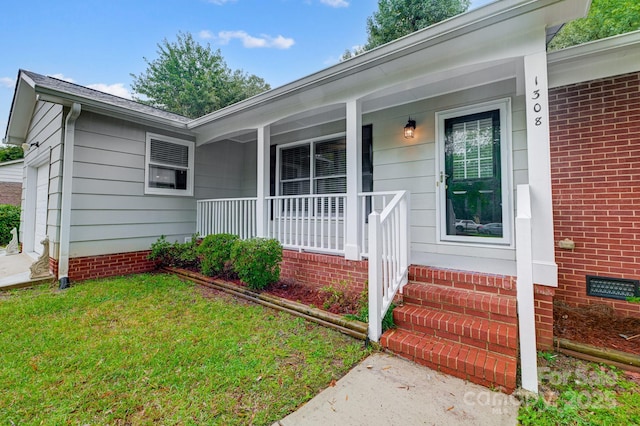 view of exterior entry featuring covered porch and a yard