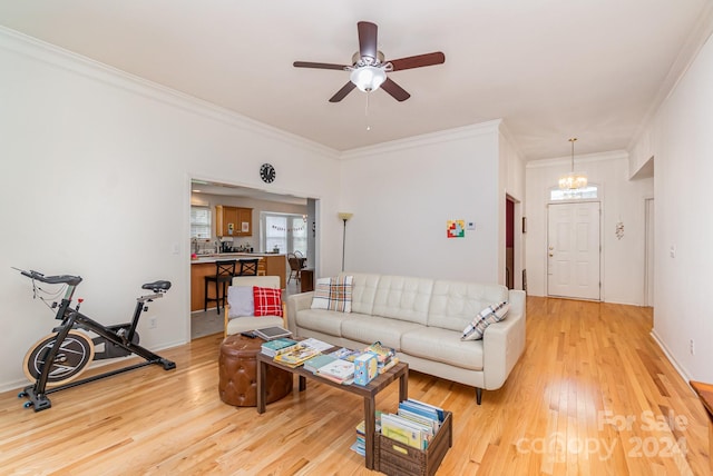 living room featuring crown molding, ceiling fan with notable chandelier, and light wood-type flooring