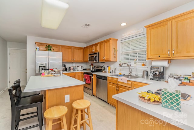 kitchen with stainless steel appliances, sink, light tile patterned floors, a center island, and a breakfast bar