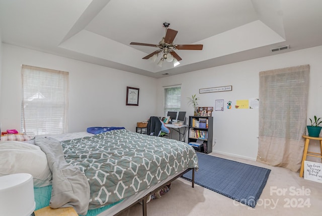 bedroom with ceiling fan, carpet floors, and a tray ceiling