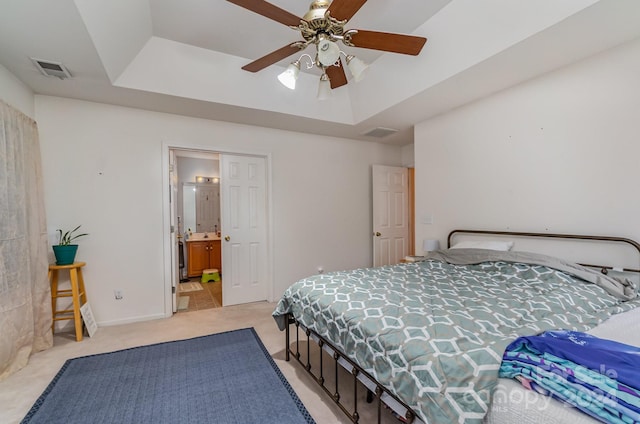 bedroom featuring light tile patterned flooring, ceiling fan, ensuite bathroom, and a tray ceiling