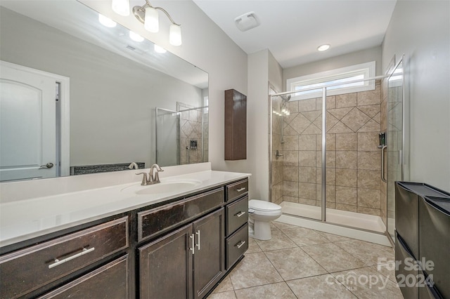 bathroom with vanity, a shower with shower door, toilet, and tile patterned flooring