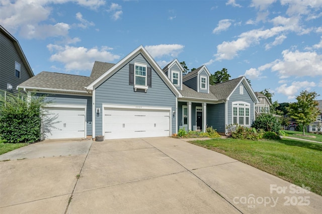 view of front of house featuring an attached garage, driveway, a shingled roof, and a front lawn