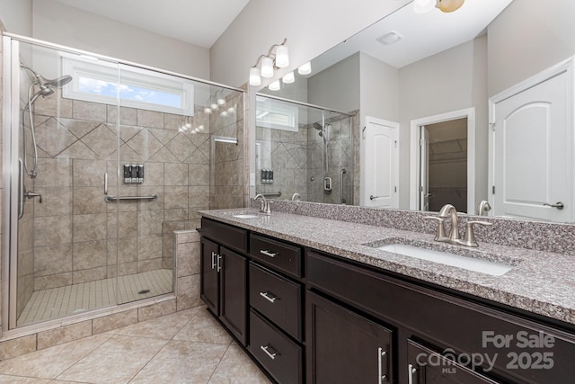 bathroom featuring double vanity, a sink, tile patterned flooring, and a shower stall