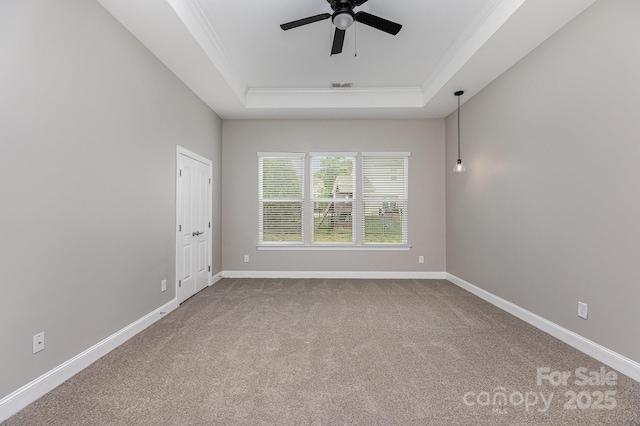 unfurnished room with visible vents, ornamental molding, carpet flooring, a raised ceiling, and a ceiling fan