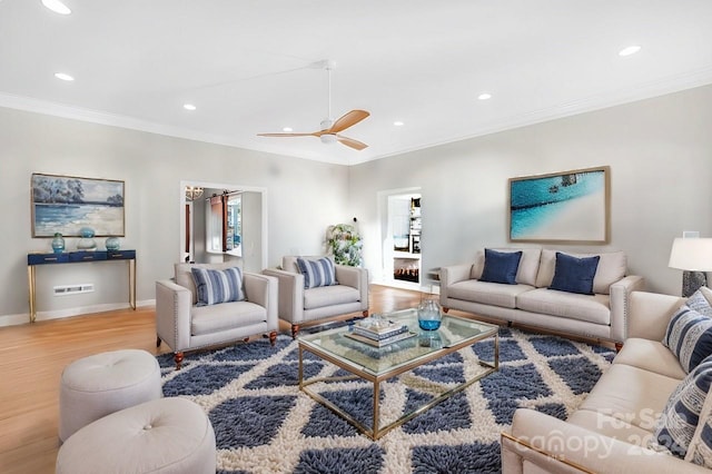 living room with light hardwood / wood-style floors, ceiling fan, and ornamental molding