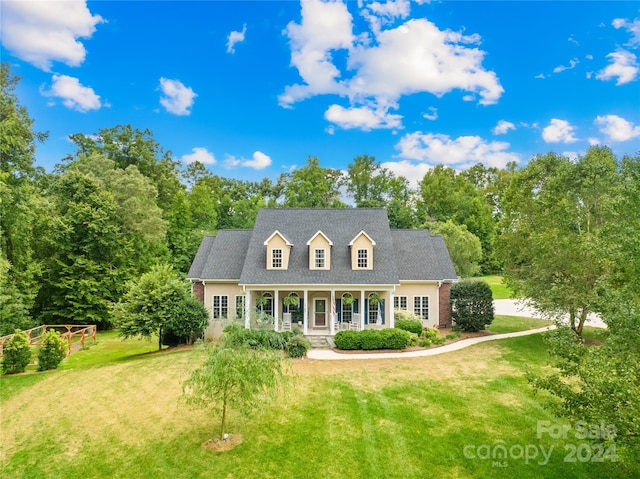 cape cod-style house featuring covered porch and a front yard