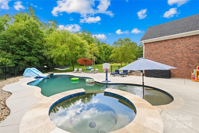 view of swimming pool with a patio area, an in ground hot tub, and a water slide