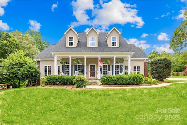 cape cod house with a porch, roof with shingles, a front lawn, and stucco siding