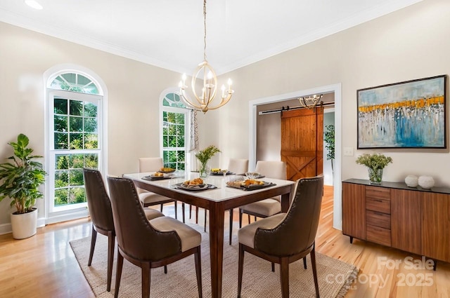 dining space featuring a notable chandelier, a barn door, light wood-style flooring, and crown molding