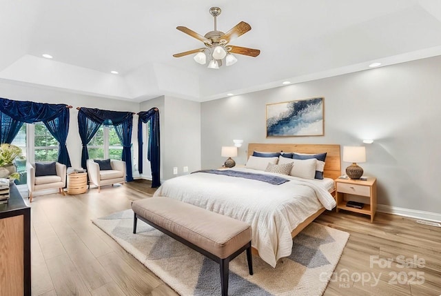 bedroom with light wood finished floors, baseboards, a raised ceiling, access to exterior, and recessed lighting