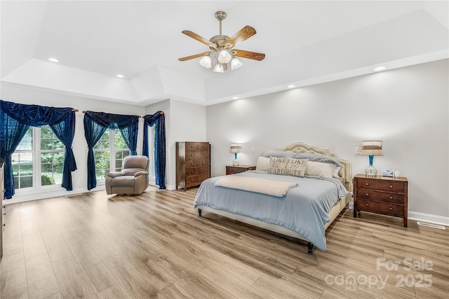 bedroom with a raised ceiling, wood finished floors, and recessed lighting