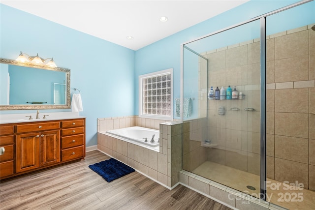 bathroom with a garden tub, a shower stall, wood finished floors, and vanity