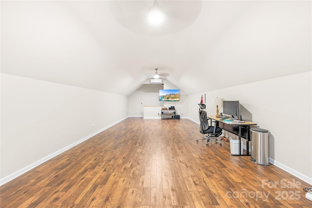 unfurnished office with hardwood / wood-style flooring, ceiling fan, baseboards, and vaulted ceiling