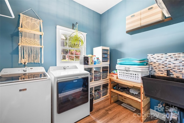 washroom with laundry area, washing machine and clothes dryer, and wood finished floors