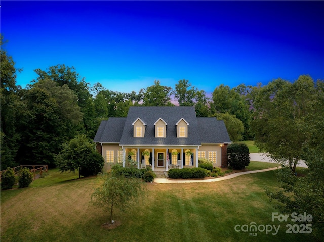 new england style home featuring covered porch and a front yard