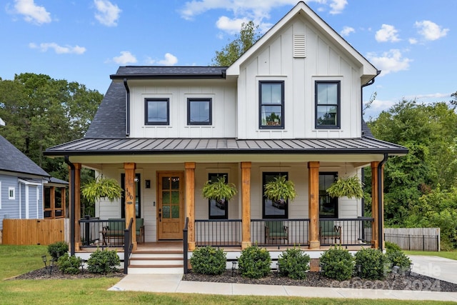 modern inspired farmhouse with a standing seam roof, fence, a porch, and board and batten siding