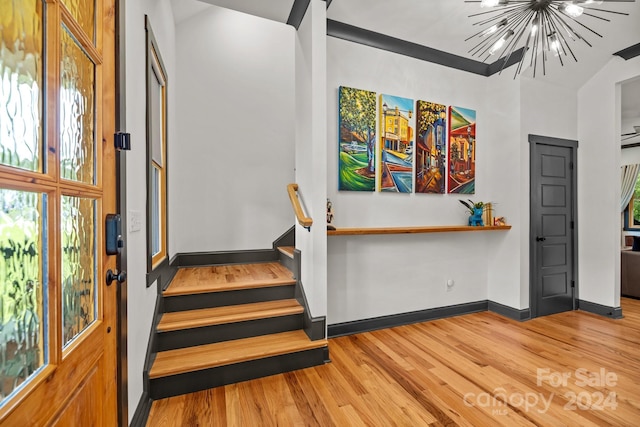 stairway featuring baseboards, wood finished floors, and an inviting chandelier