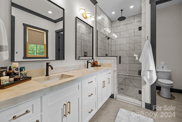 full bath featuring double vanity, a shower stall, toilet, and a sink