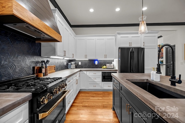 kitchen featuring premium range hood, hanging light fixtures, black appliances, and white cabinetry