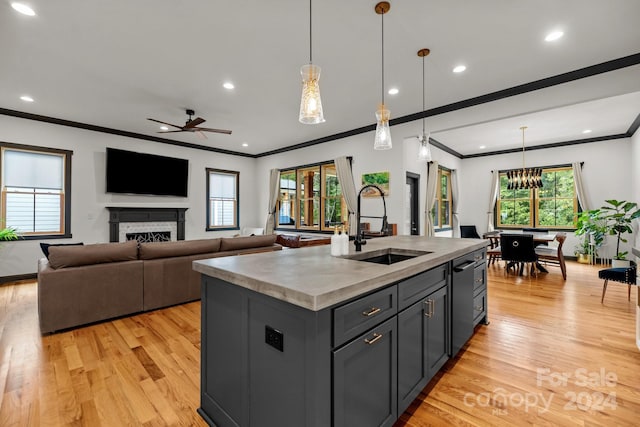 kitchen featuring pendant lighting, open floor plan, a kitchen island with sink, and a sink