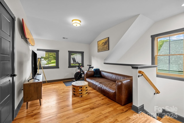 living room featuring light wood-type flooring, visible vents, vaulted ceiling, and baseboards