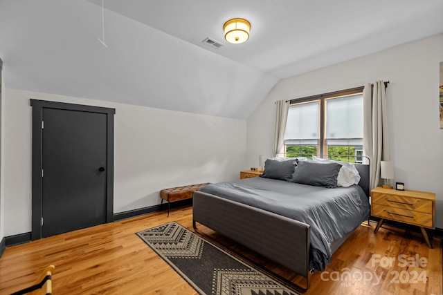 bedroom with lofted ceiling, visible vents, and wood finished floors