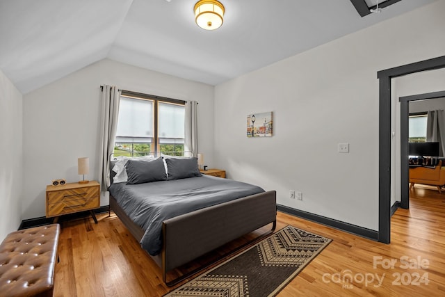 bedroom featuring lofted ceiling, baseboards, and wood finished floors